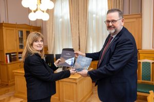 Kvinne til venstre og mann til høyre, holder to årsmeldinger mellom seg